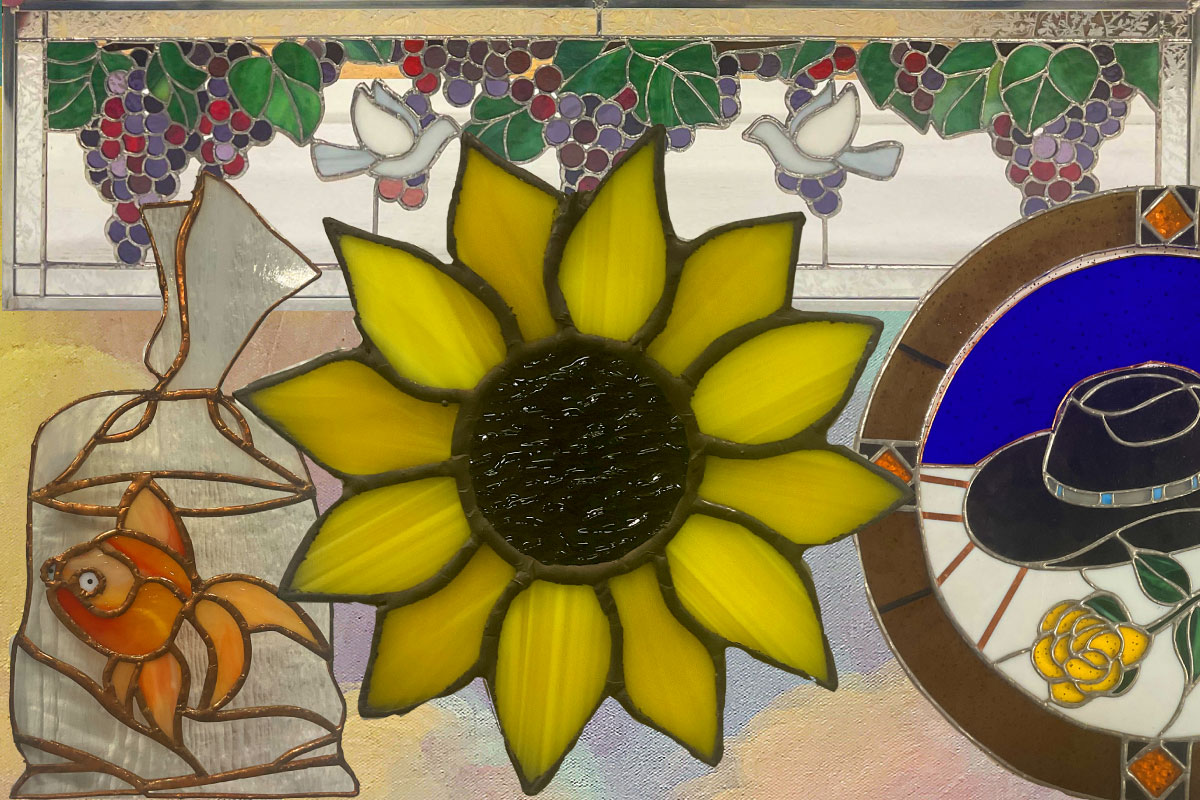 Stained glass piece with a goldfish in a bag, a sunflower and a southwest cowboy hat.