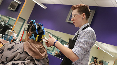 A san Juan College Cosmetology student installing a perm on a customer.