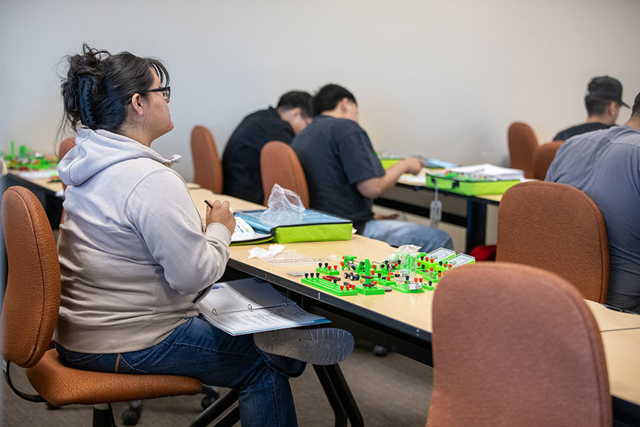 Students in a community college classroom work on hands-on projects and review application materials, representing the steps of how to apply for community college and prepare for admission before important deadlines.