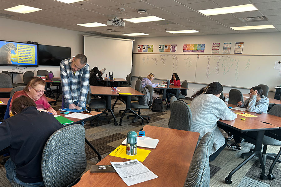 Adult students in a classroom GED prep course working with an instructor at a community college