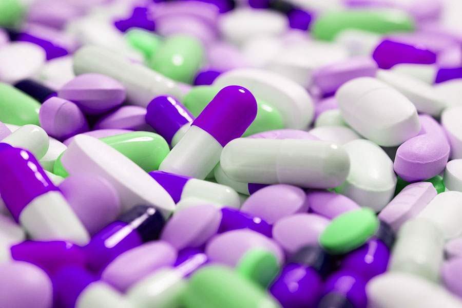 Stack of pills capsules in purple, white and green