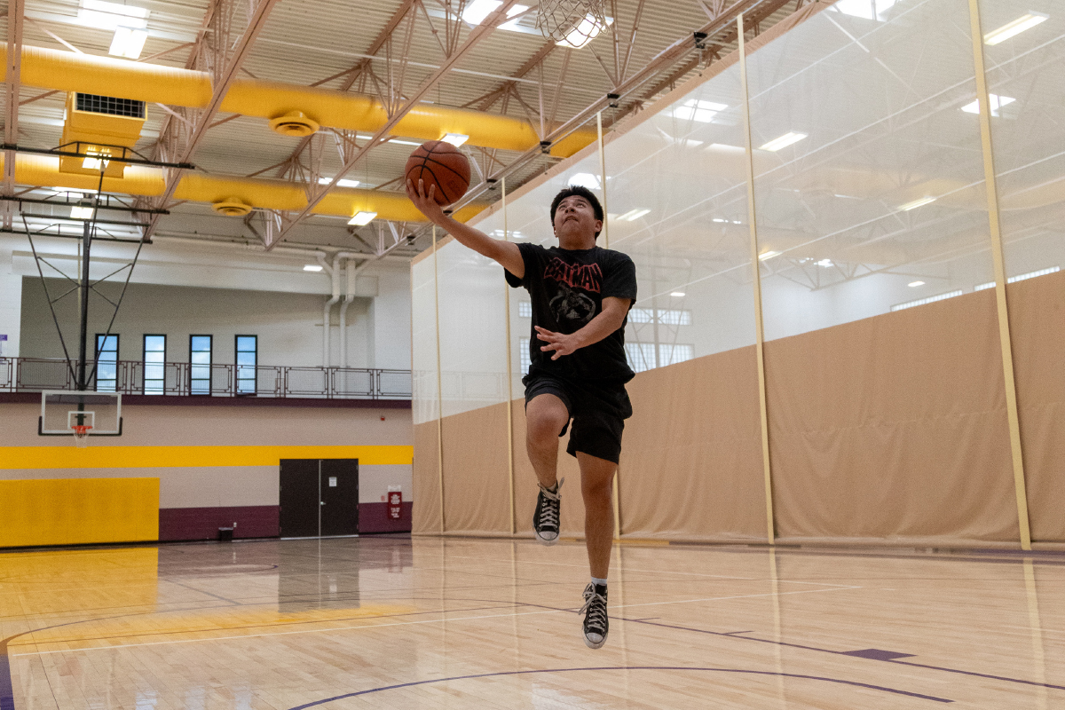 A SJC Student playing basketball jumping to the hoop