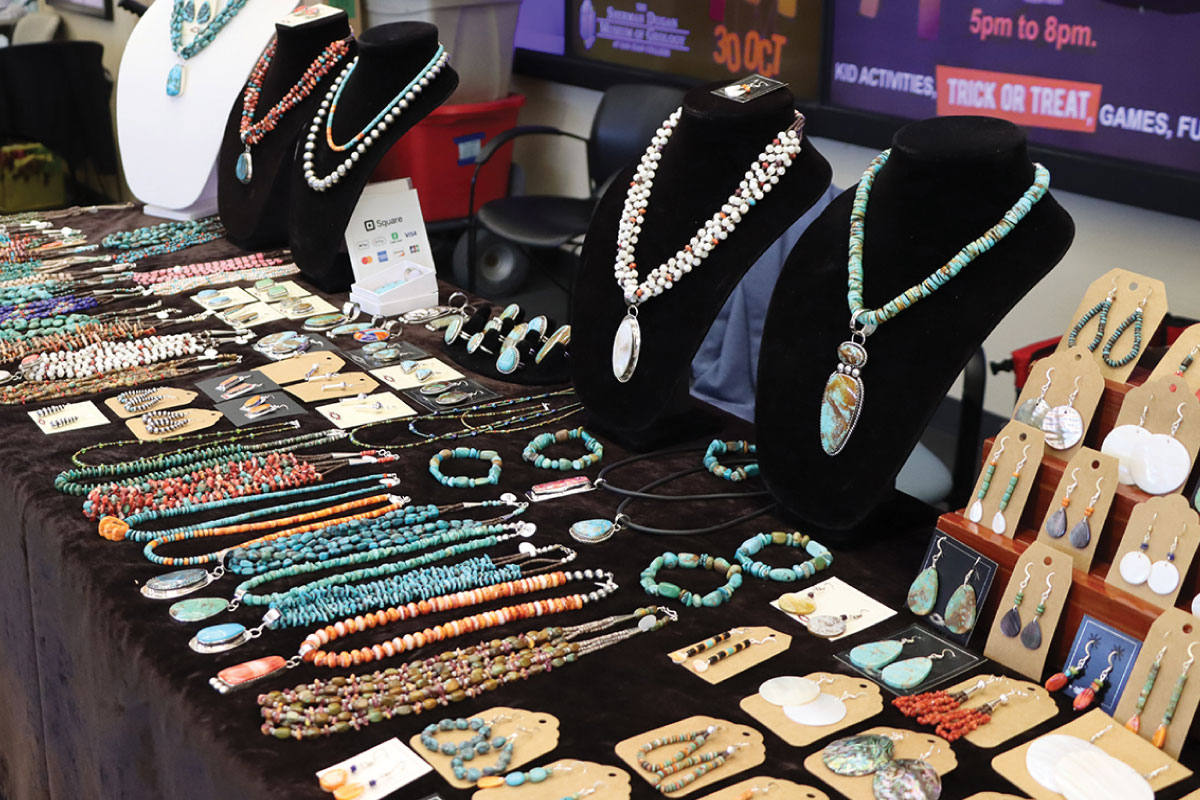 A collection of Native American jewelry laying on a table, necklaces, earrings and rings