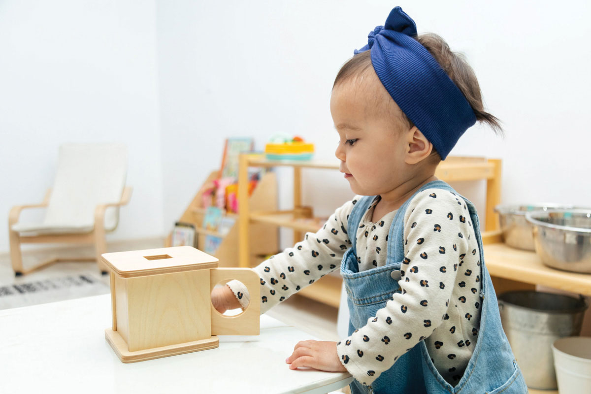 Small toddler playing with a wooden learning shape box