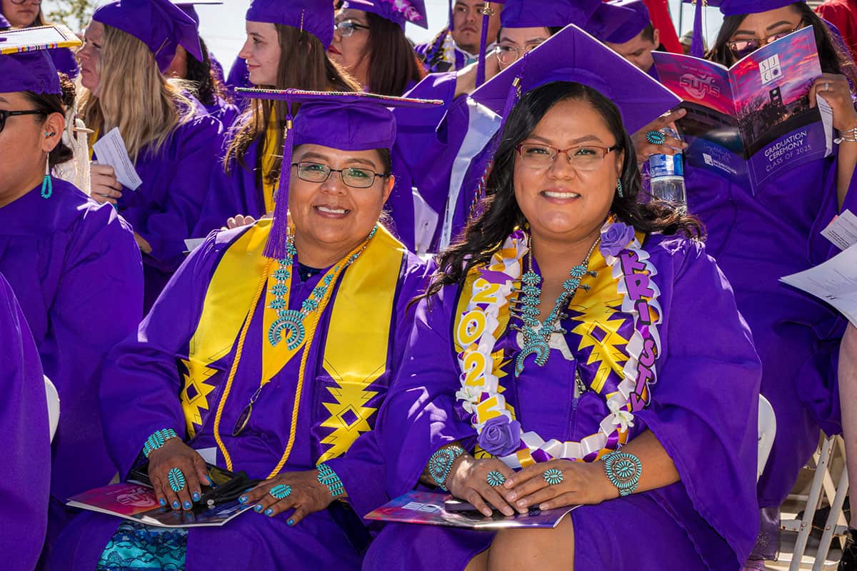 Two SJC Students in their purple caps and gowns with gold stoles