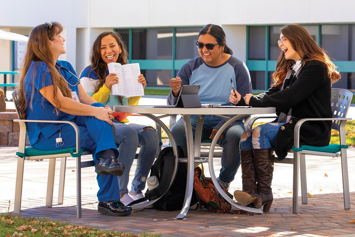 SJC Students in the Courtyard on main campus at a table laughing as they are studying