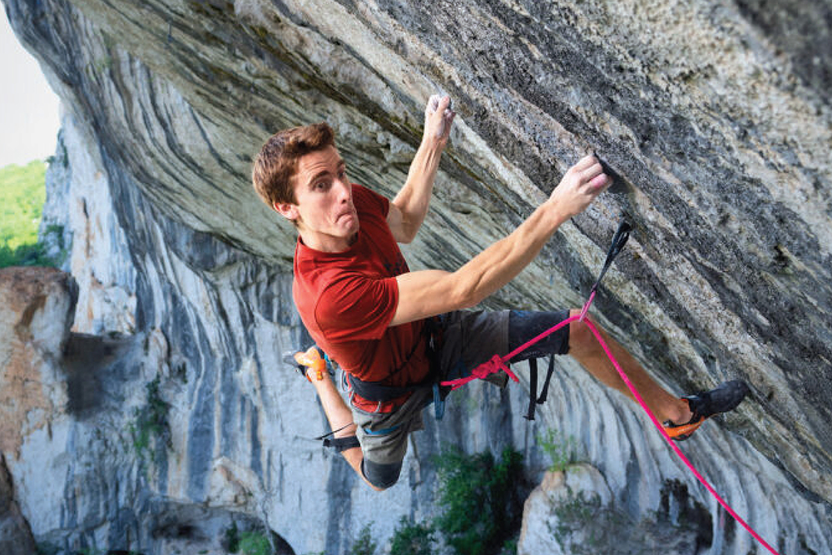 Woman rock climbing with water below