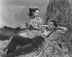 Snip From the Our Town movie in black and white, two individuals sitting on a hay stack