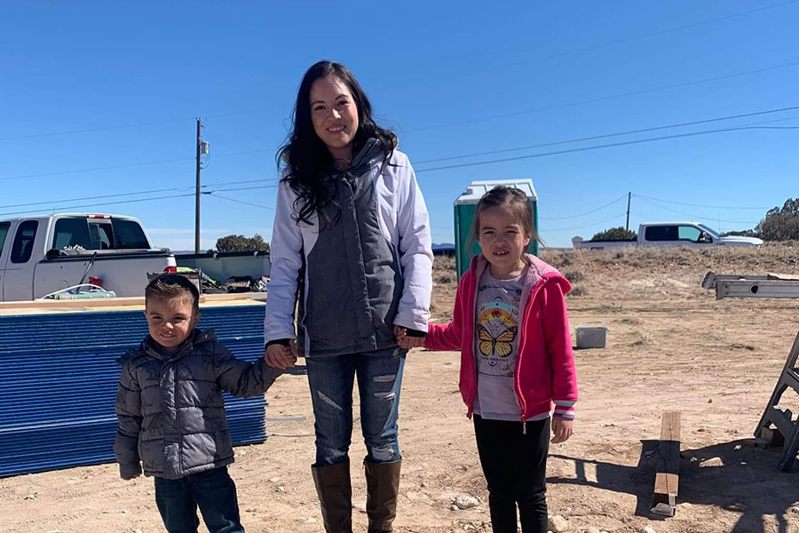 Woman and two children stand on site of new Habitat for Humanity homebuild.