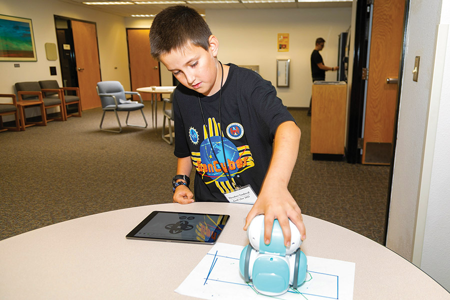Young GenCyber student works with mini robot the Artie 3000 while attending the science camp.