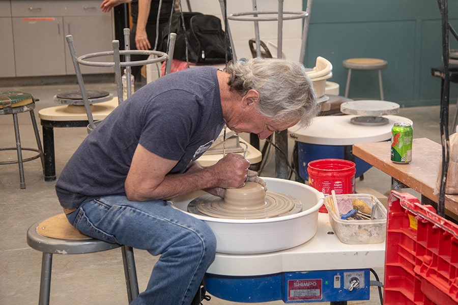 Adult students works on a potter's wheel in a Continuing Education class.