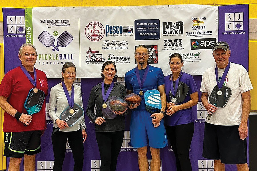 Group of individuals with their medals and their pickleball paddles.