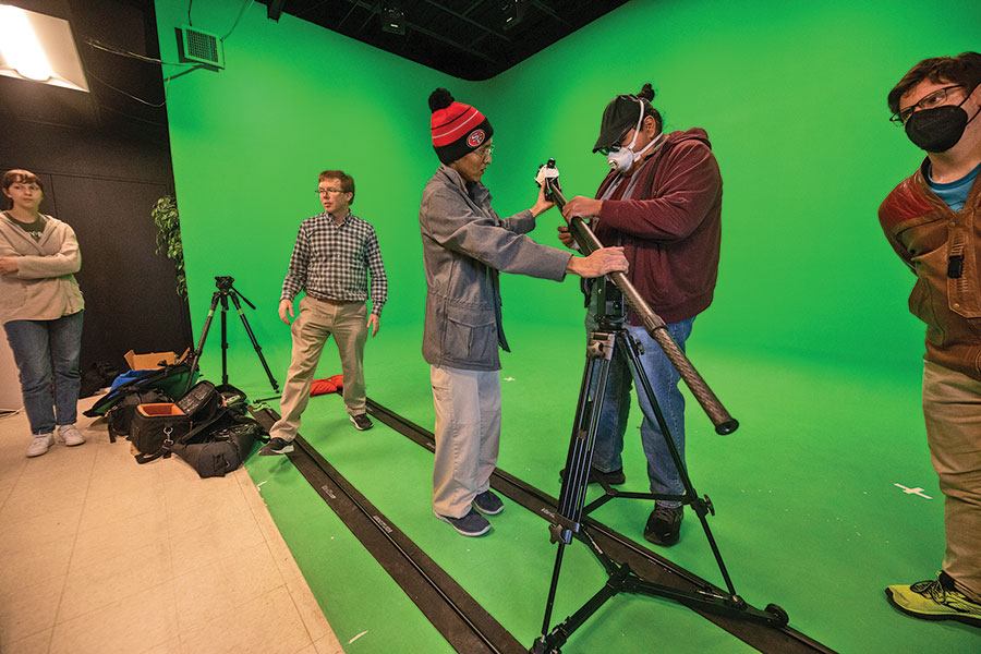 Students getting video equipment together in front of a green screen