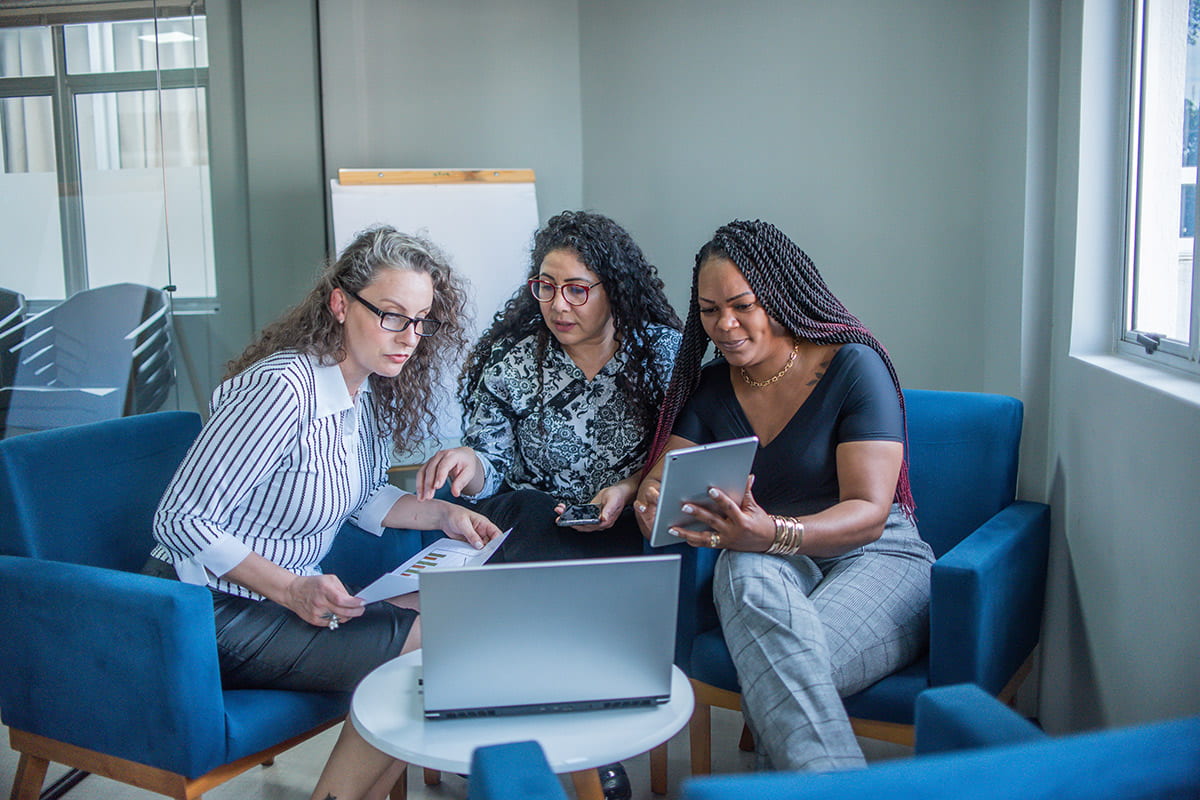 Three students confidently working together in front of a laptop.