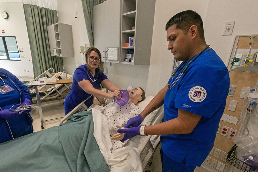 Nursing students practice patient care with medical dummy.