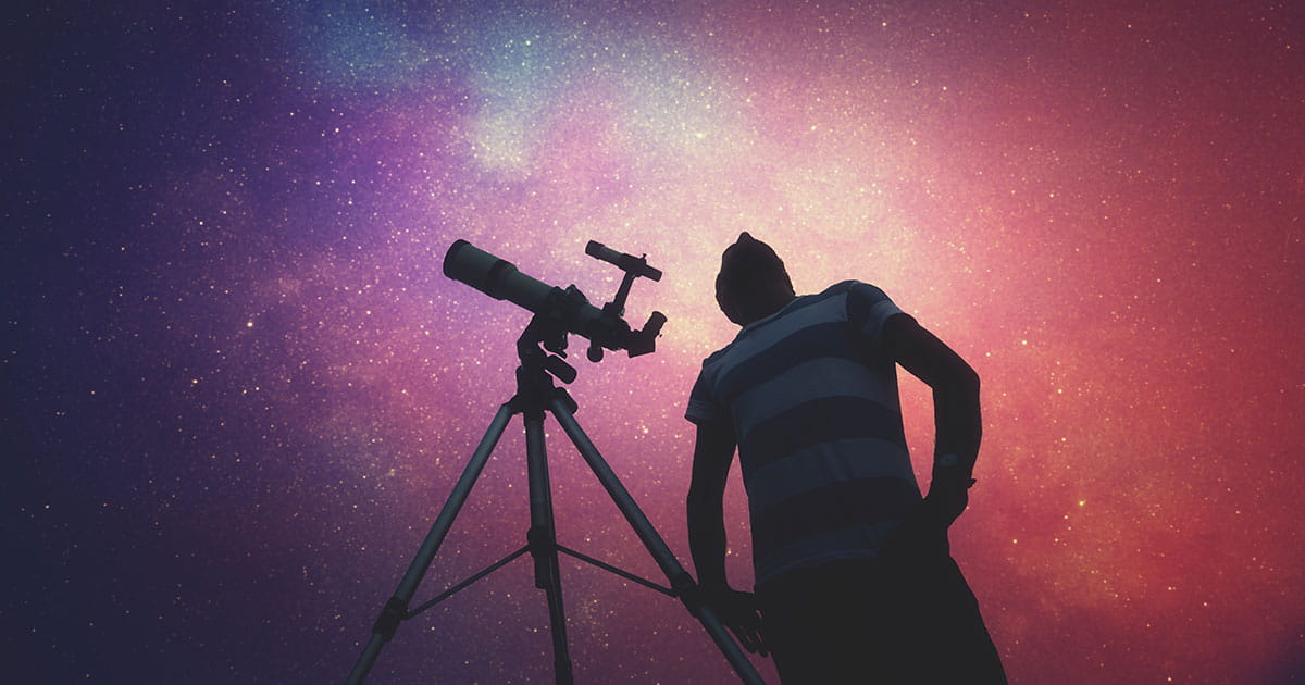 Man standing beside telescope