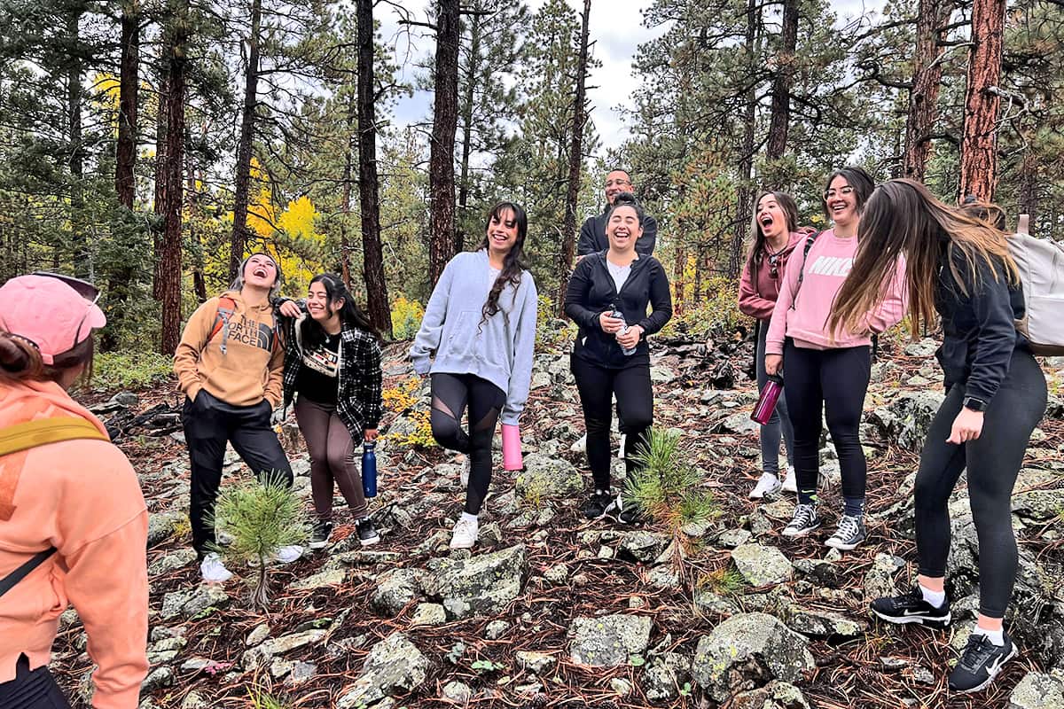 Estudiantes embajadores riendo y divirtiéndose mientras realizan una caminata por la naturaleza durante un ejercicio de desarrollo.