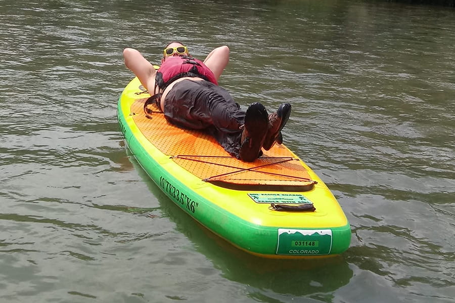 Individual laying on paddleboard floating on water