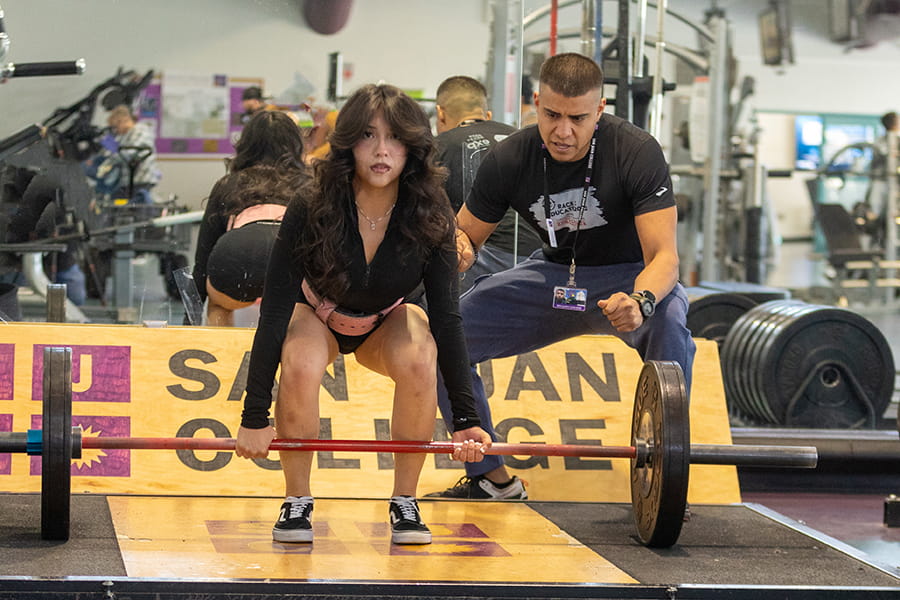 One student liftin a weight and another spotting